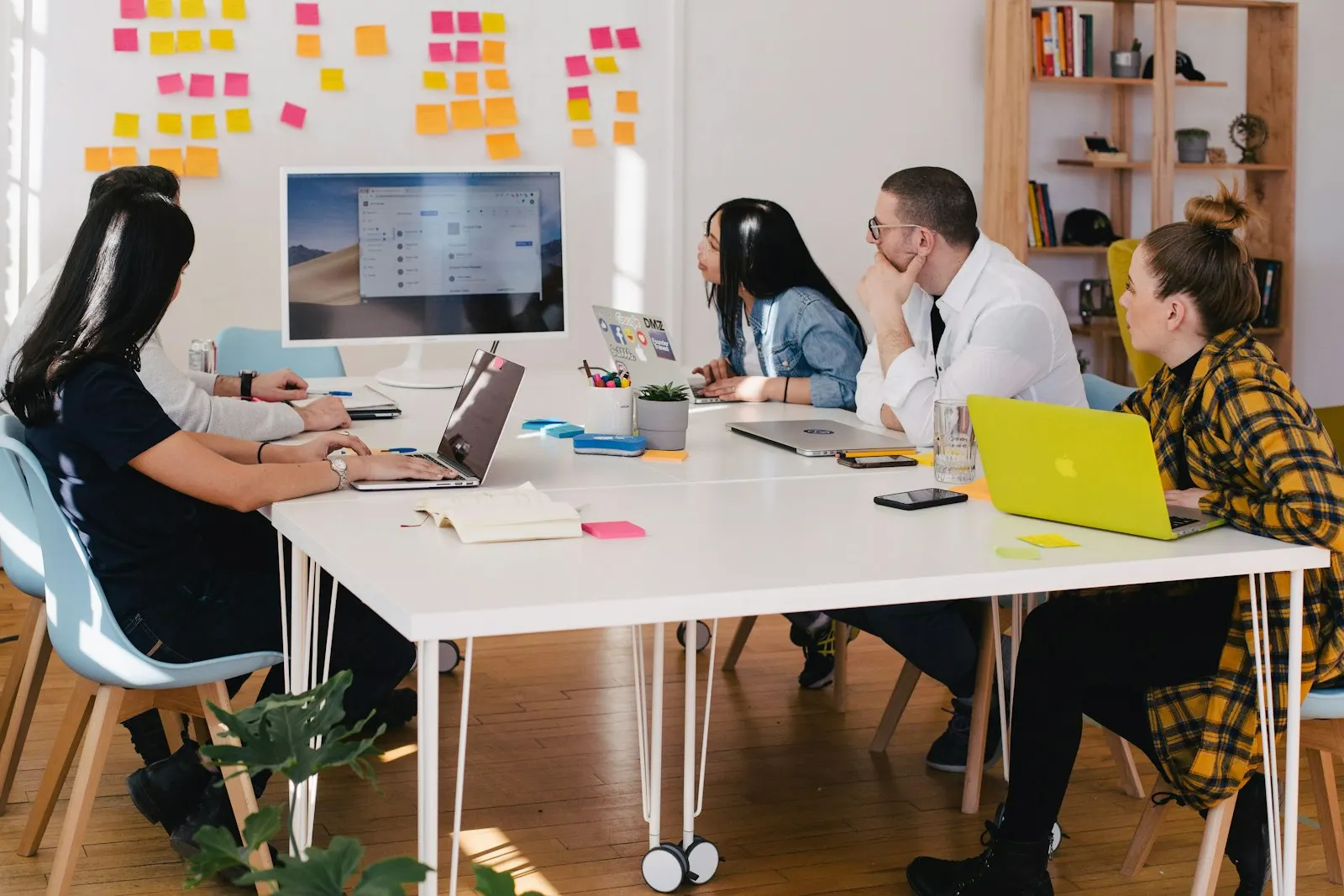 An MVP squad at laptops in a bright office, with a wall of sticky notes planning the sprint.