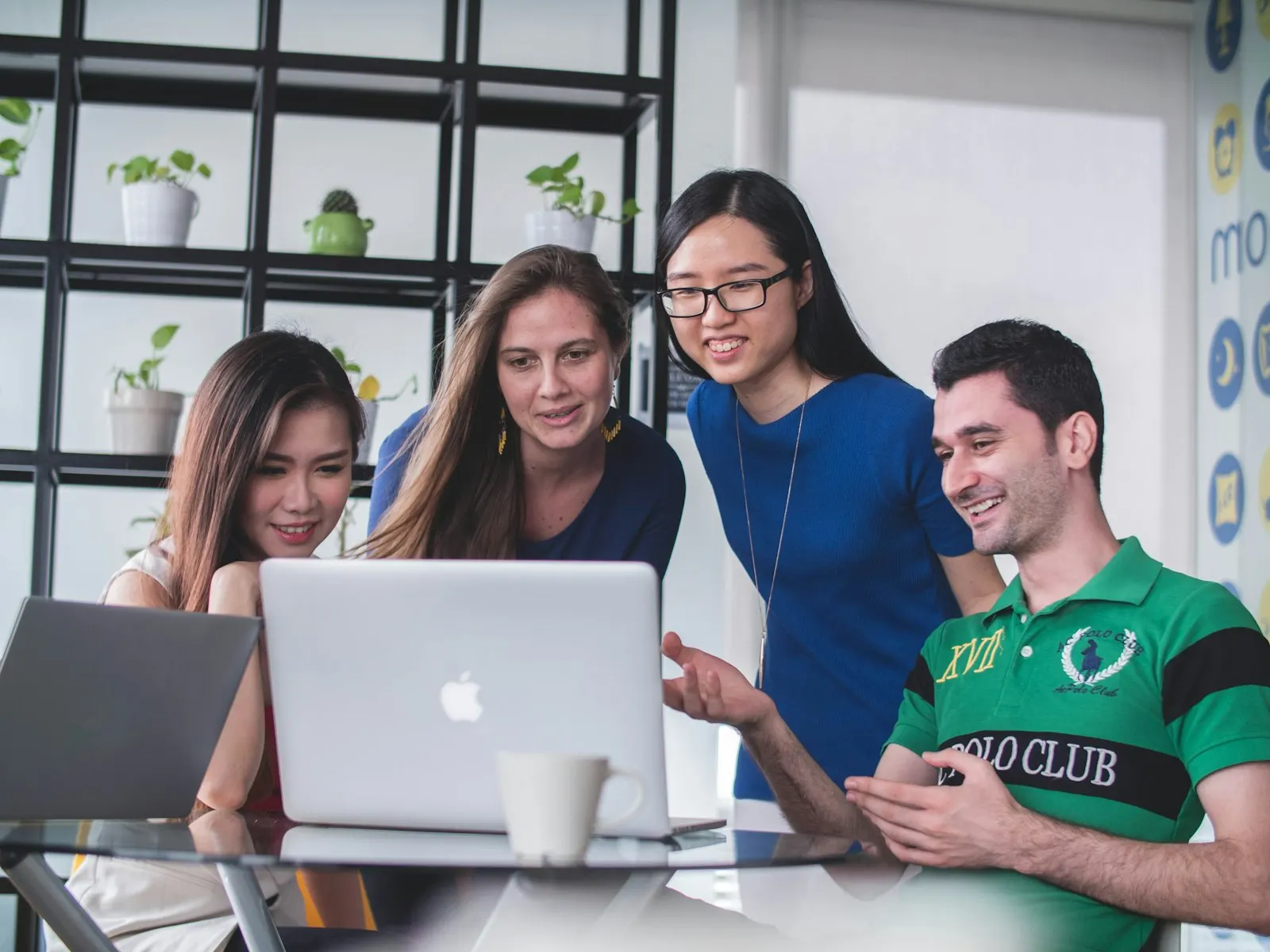Four colleagues on an MVP development team gather around one laptop.