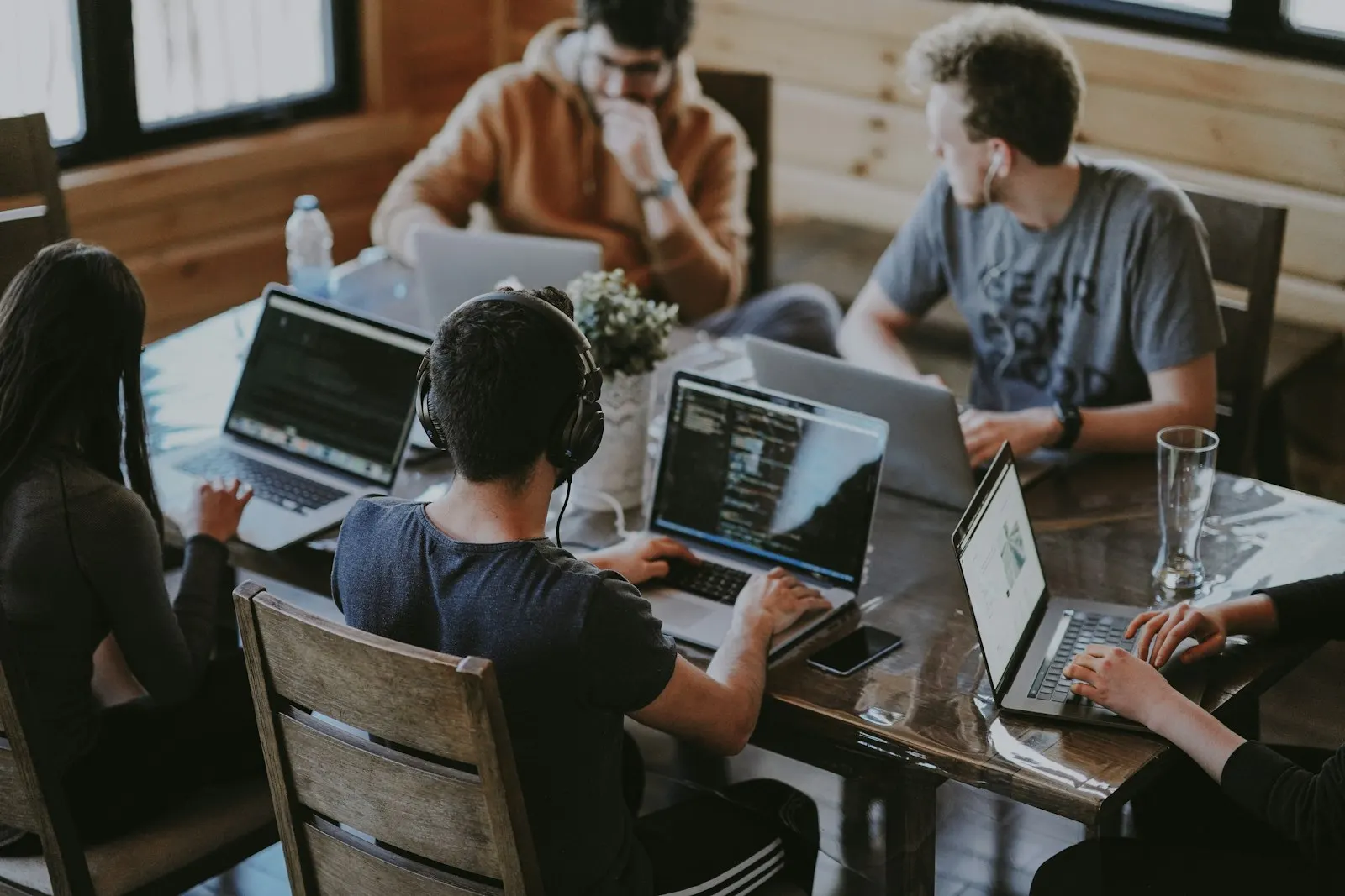 An MVP development team working side by side at laptops around one long table.
