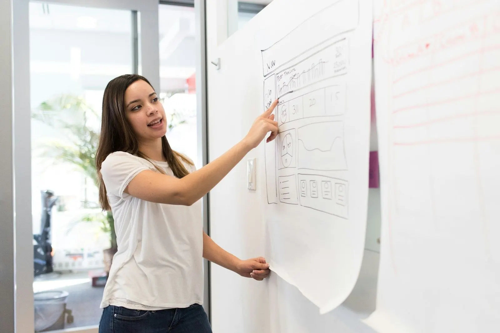 A design system lead sketches a wireframe on a large sheet of paper on the wall.