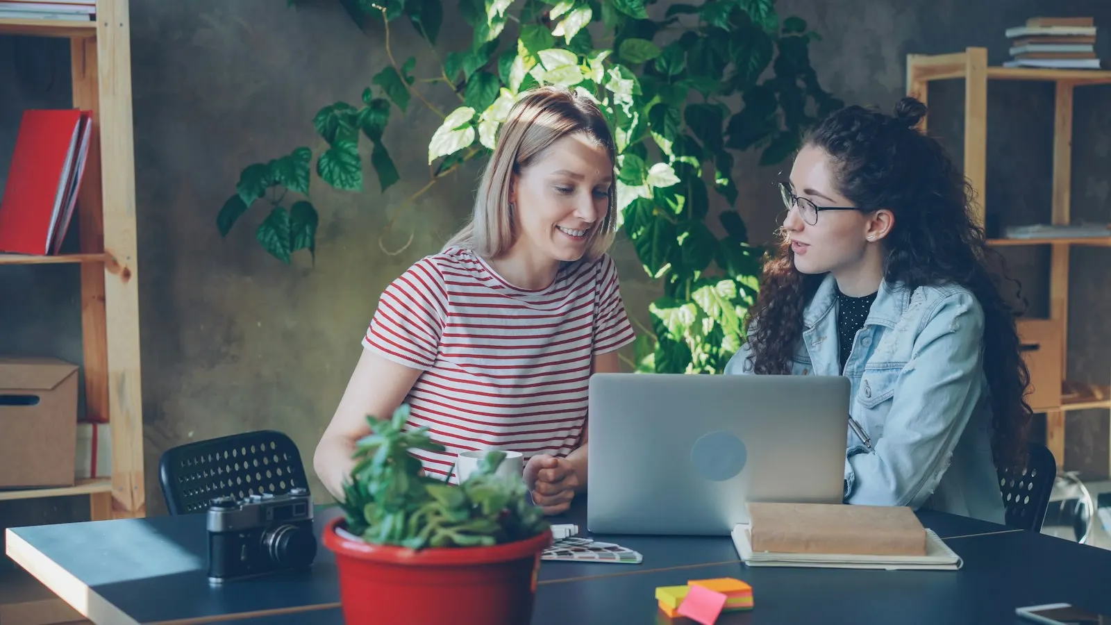 Two UI/UX designers review a screen together at a laptop.