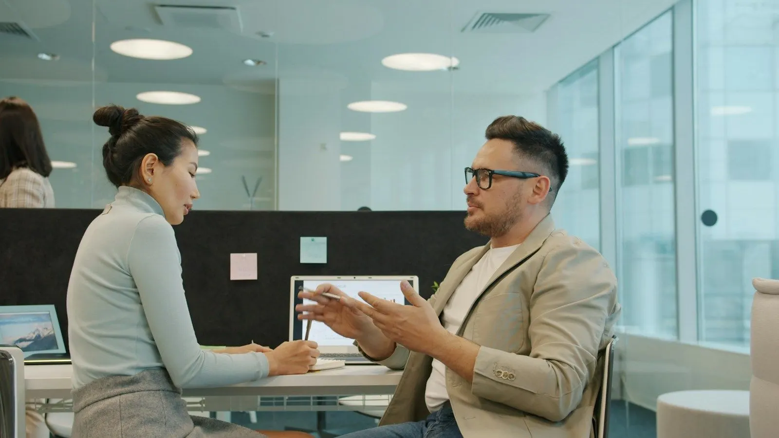 Two colleagues discussing how to hire UI/UX designers over a tablet in a modern office.