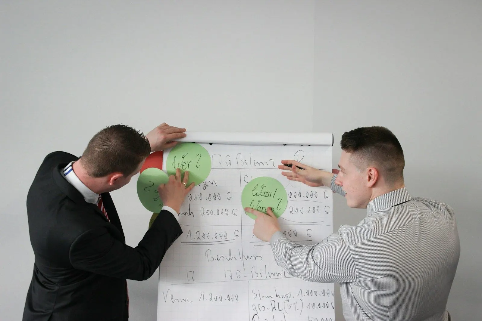 A business process analyst working through a diagram on a flip chart with a colleague.