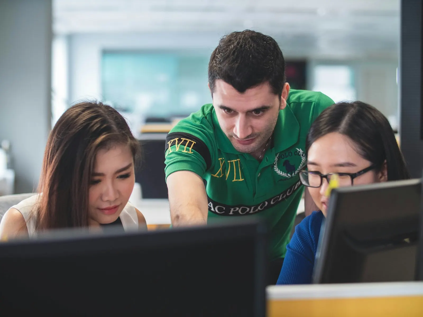 A senior React developer pointing out a change on a colleague’s monitor.