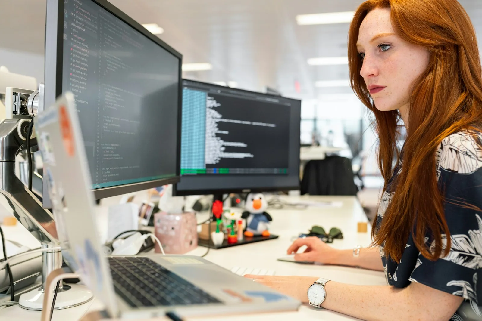 A React developer writing code across two large monitors at her desk.