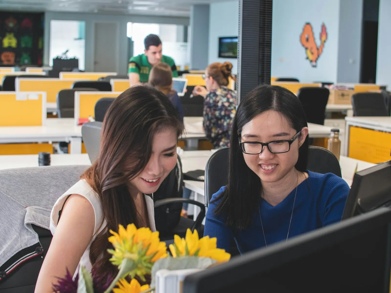 Two fullstack developers smiling as they review code together at a desk.