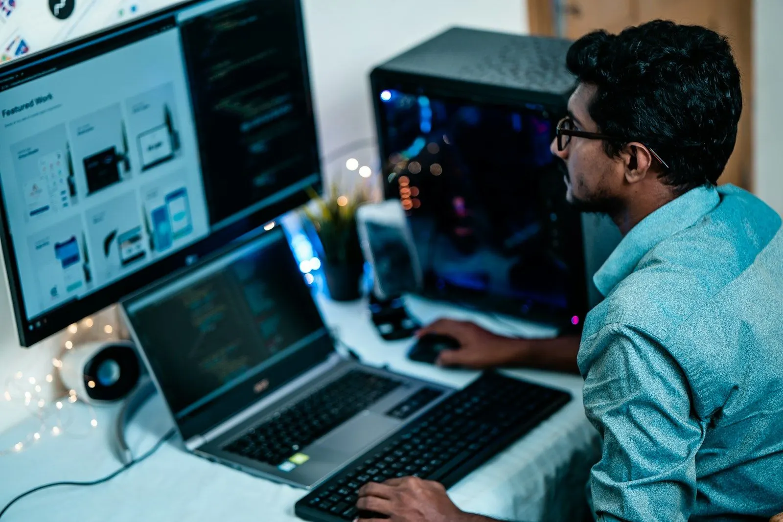 A fullstack engineer working across a laptop and a monitor at a busy desk.