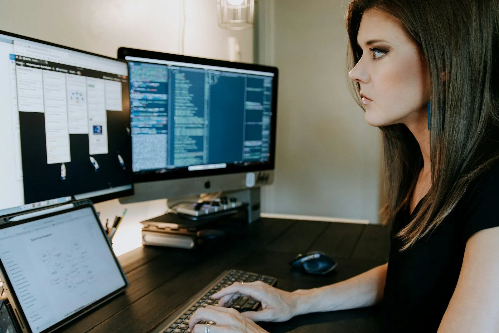 A fullstack solutions architect focusing on code across two monitors and a laptop.