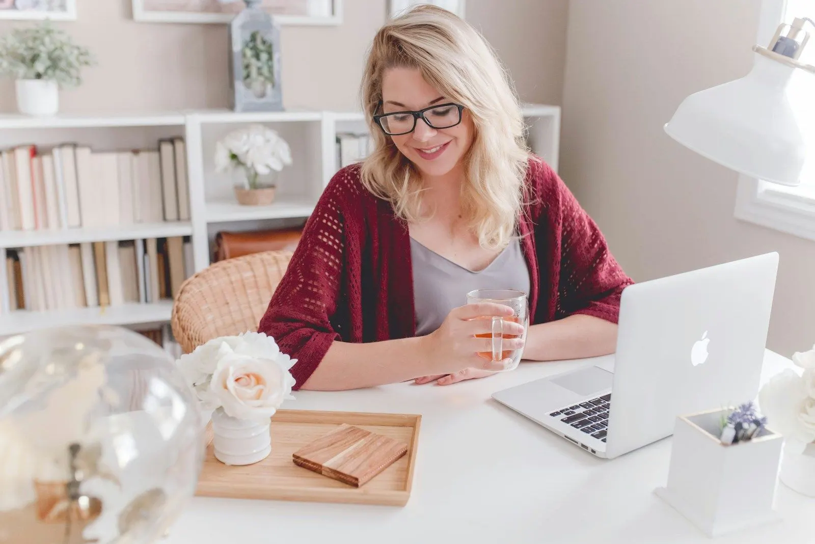 A fullstack systems engineer smiling at her laptop at a white desk at home.