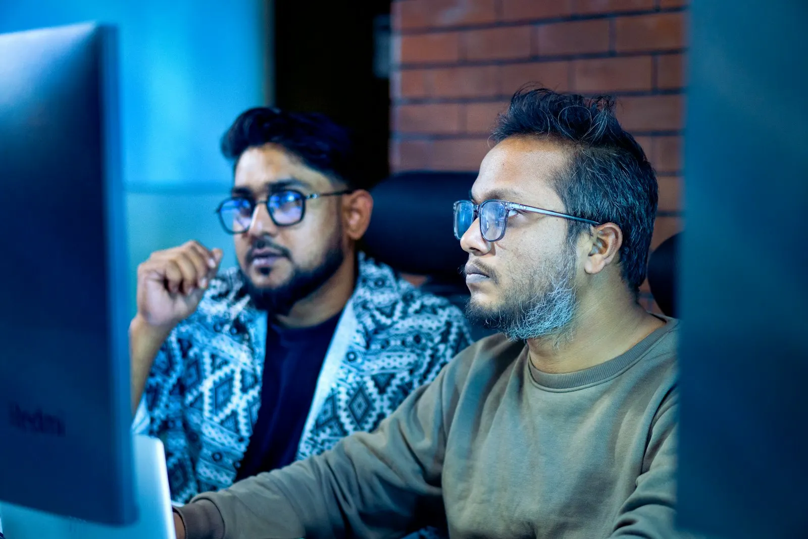 Two Node.js engineers watching a load test on a monitor in a dim room.