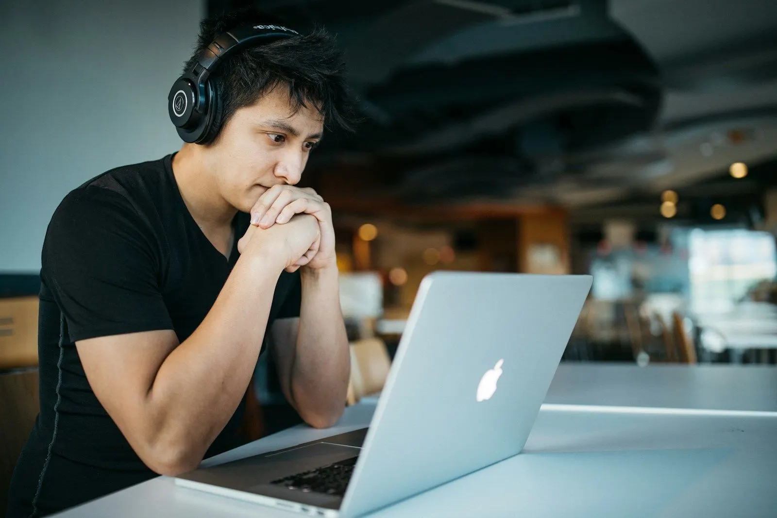 A Node.js real-time engineer in headphones studying his laptop screen at a cafe table.