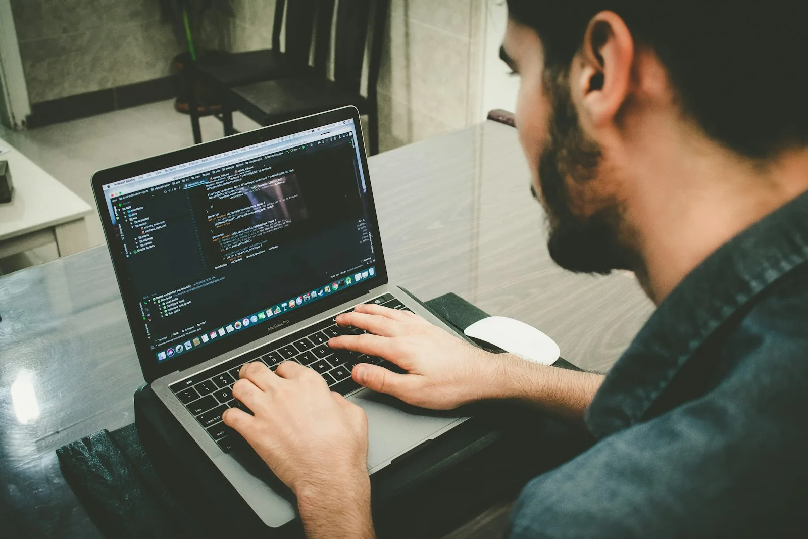A Python developer writing code on a laptop at a desk.
