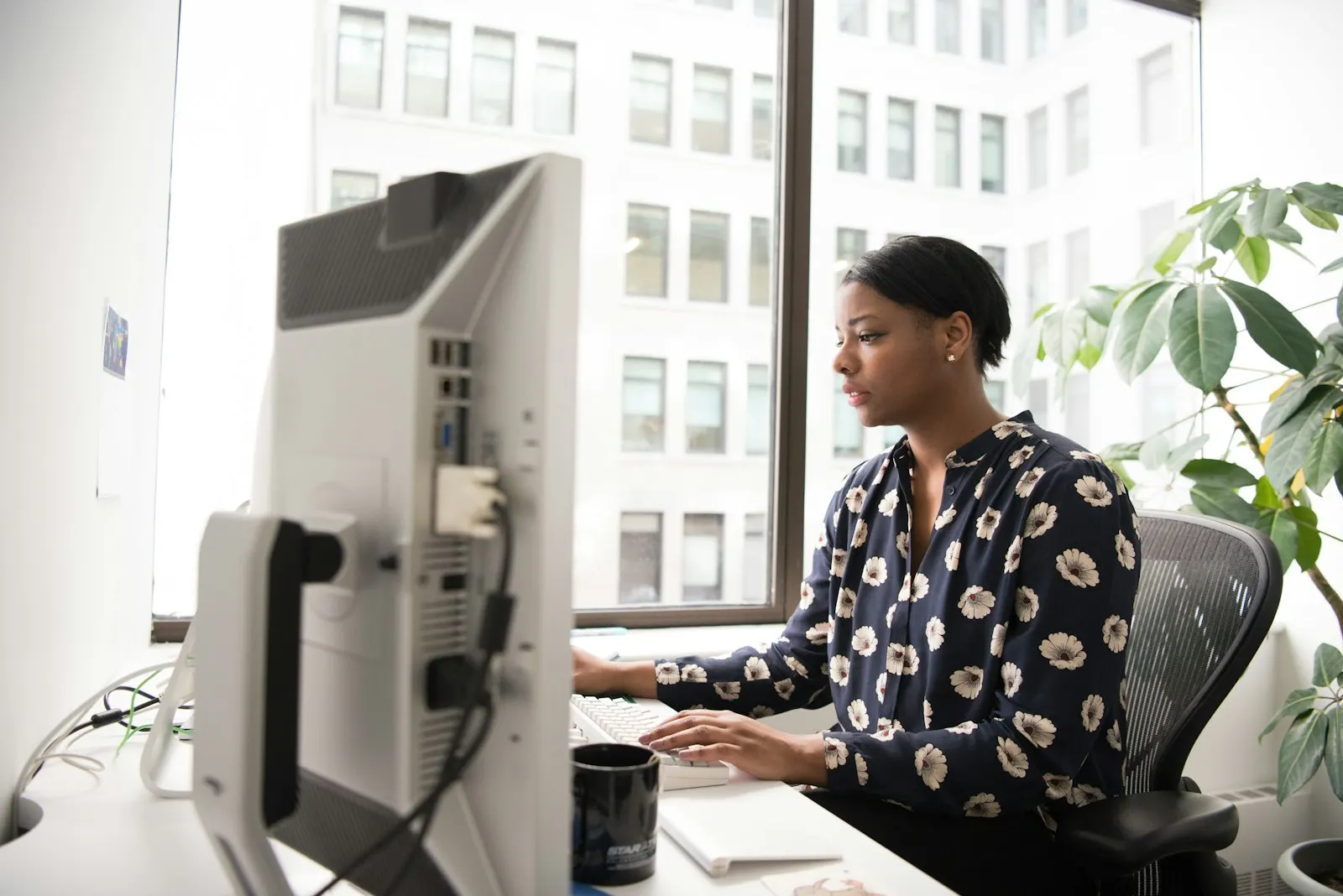 A Python engineer working at a desktop computer in a bright office.