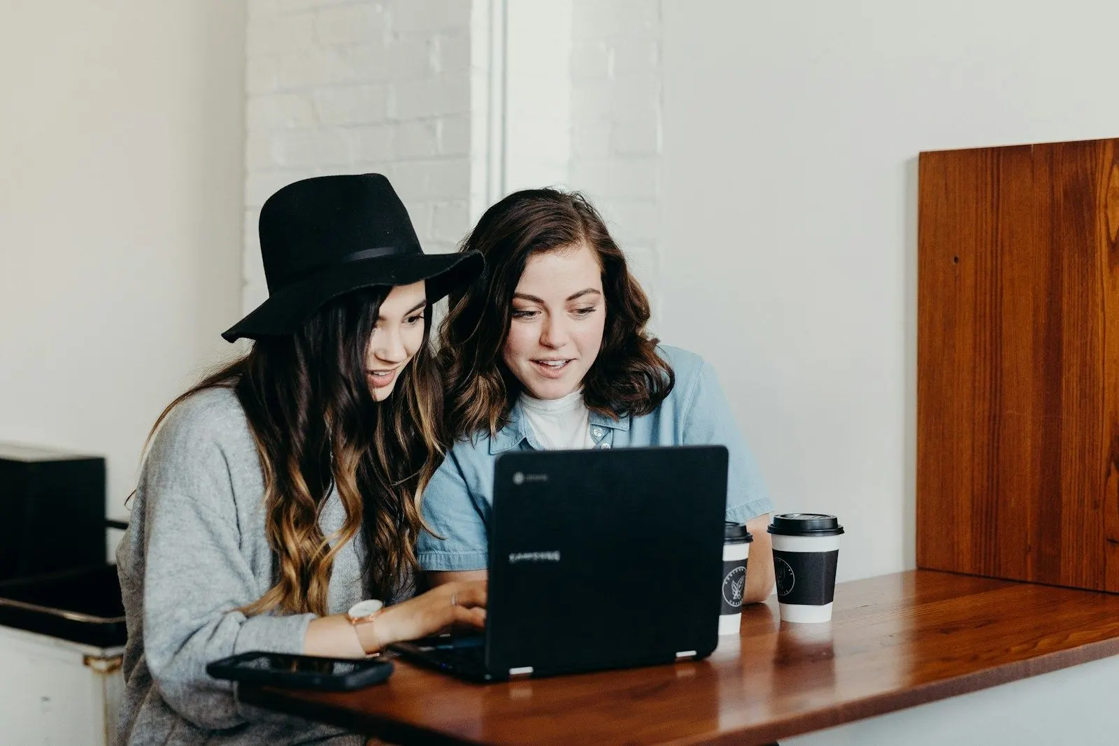 Two Python ML engineers working through a model together on a laptop at a cafe table.