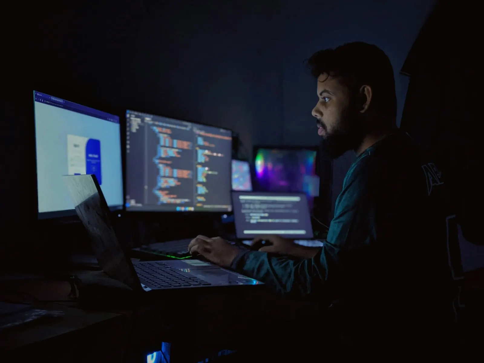 A Python developer working late across three monitors of code.