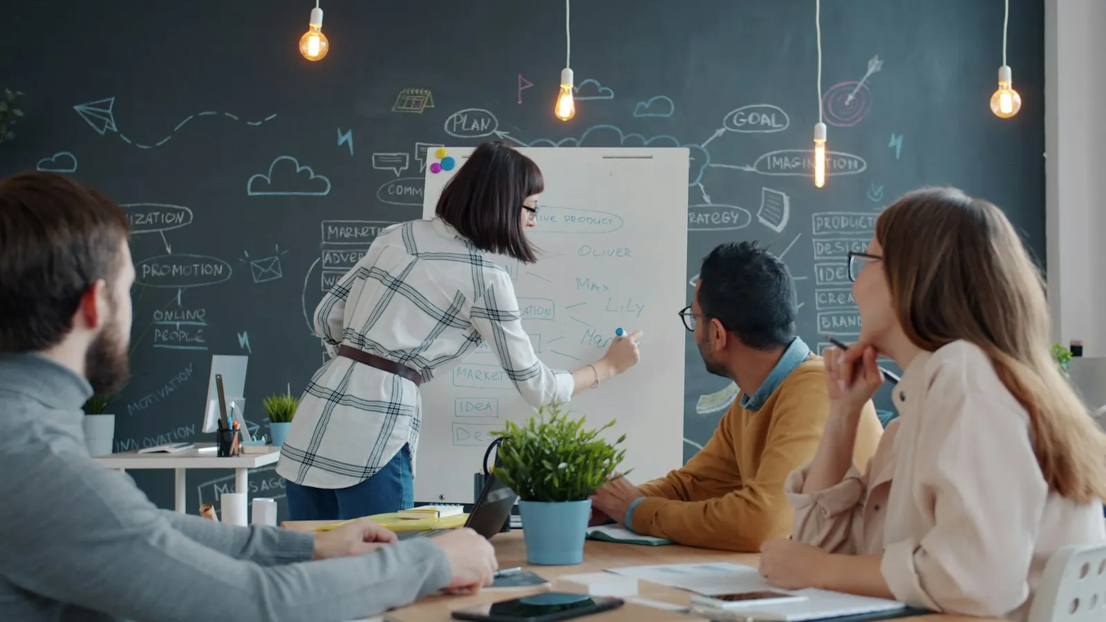 A .NET team planning at a whiteboard while colleagues listen at the table.