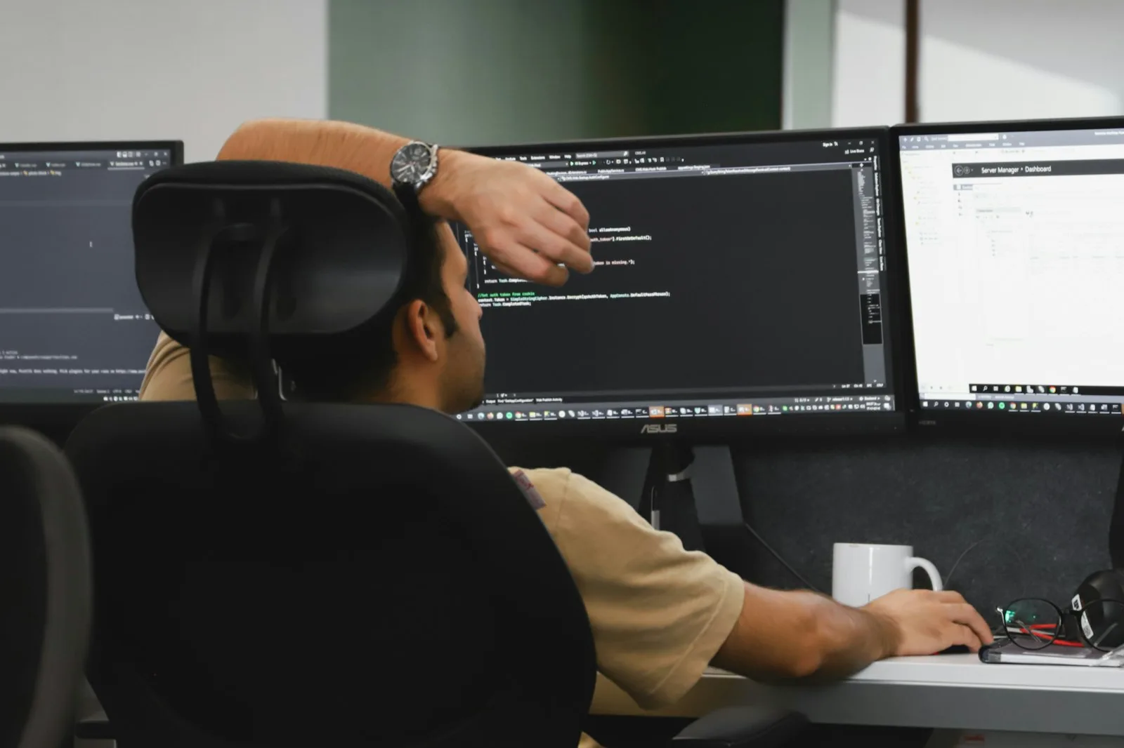 A .NET developer working through code across two monitors.