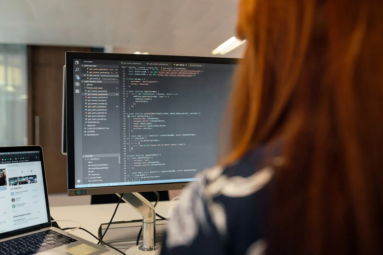 A .NET engineer reading code on a large monitor at her desk.