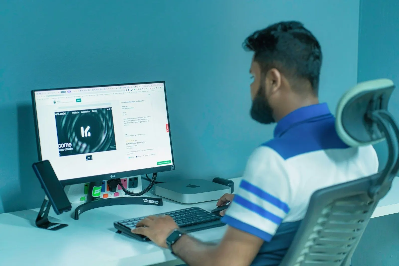 A .NET architect in a striped polo working at a monitor on a standing desk setup.