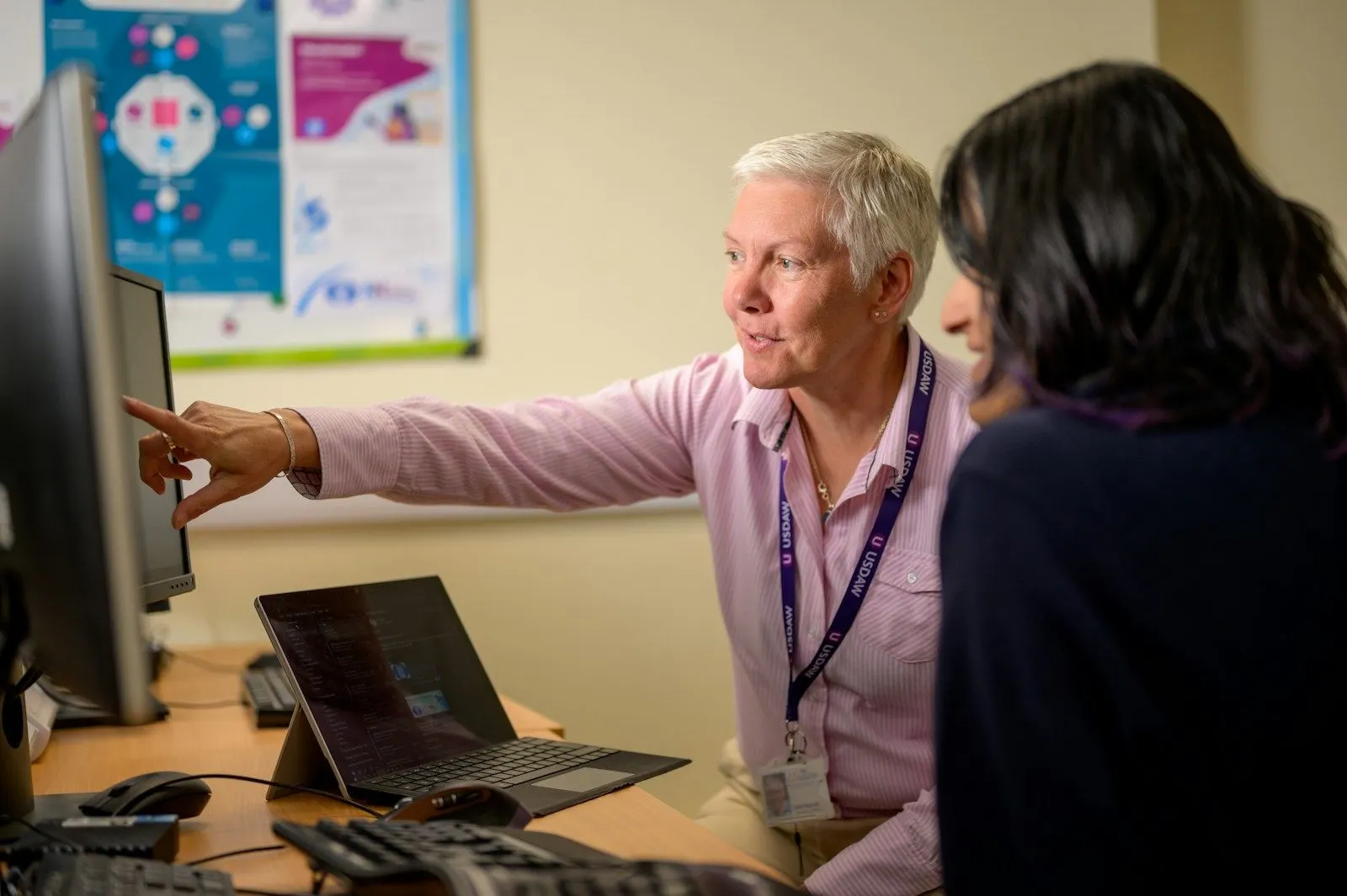 A .NET migration engineer pointing out something on screen to a colleague.