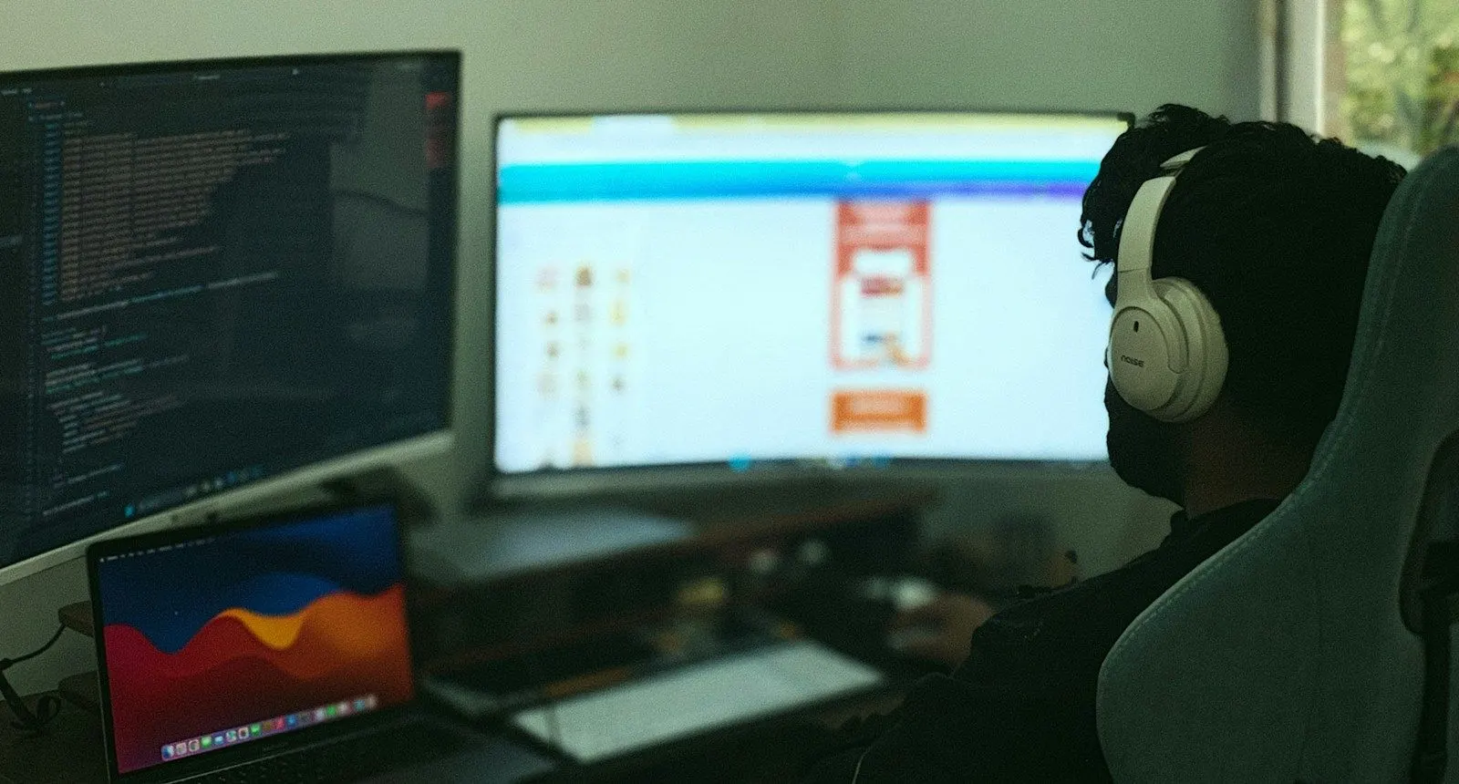 A Java architect in headphones working across several large monitors in a dim room.