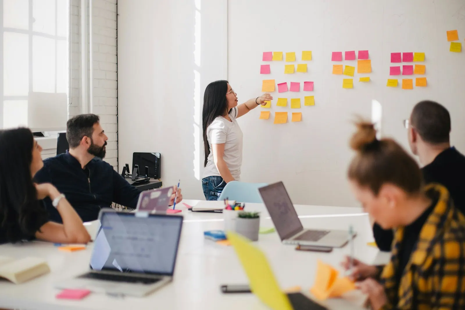 A product discovery workshop: a lead maps ideas on sticky notes while the team works through them at their laptops.