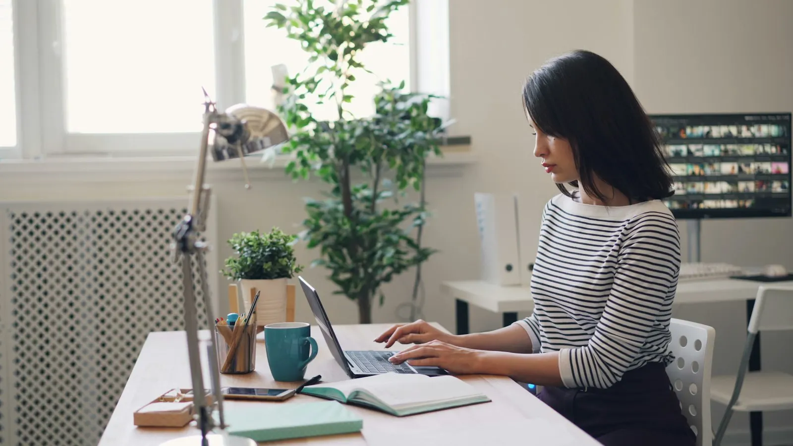 A PHP engineer working through code on her laptop at a bright desk.
