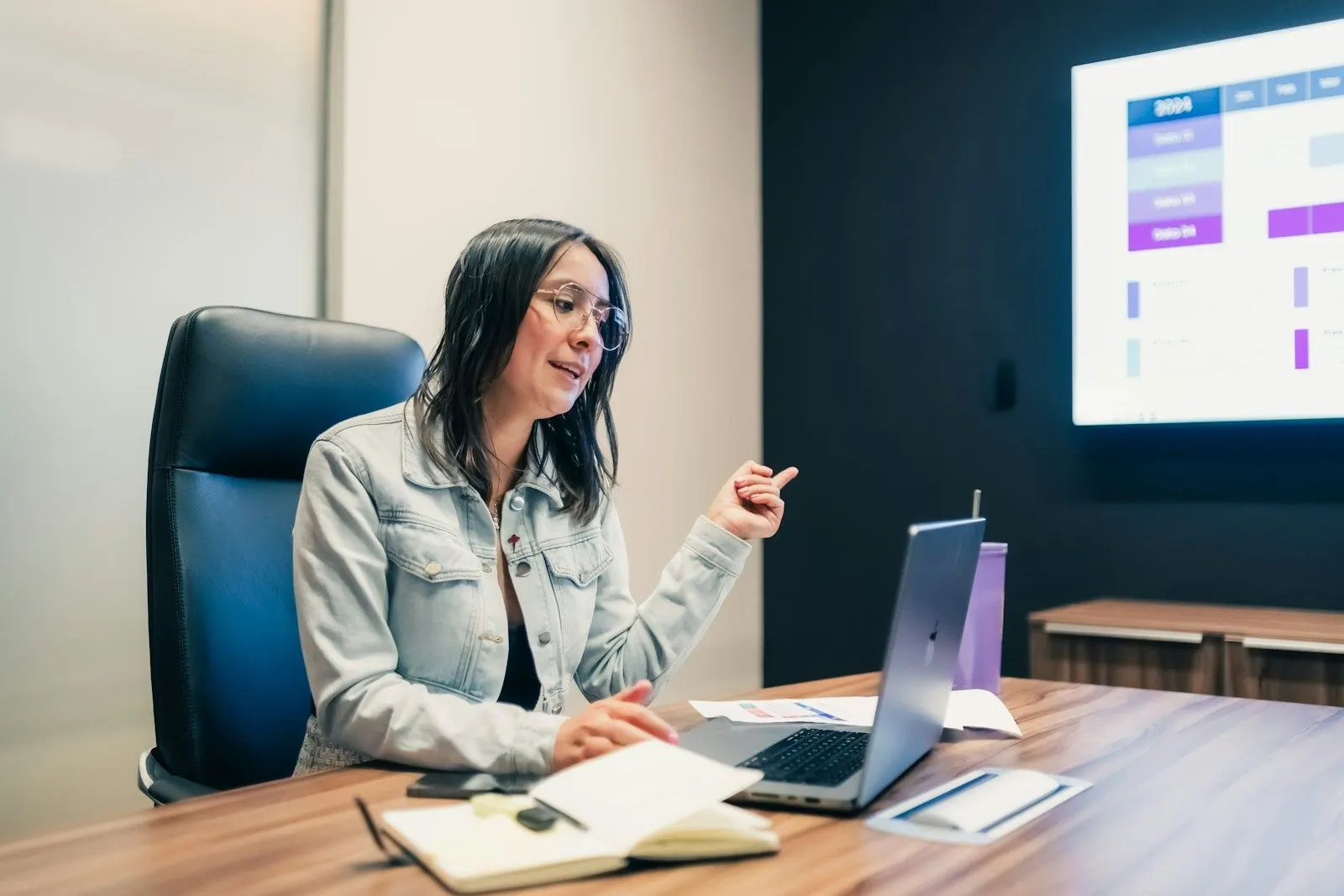 A colleague explaining how to hire React Native developers at a meeting table with her laptop.