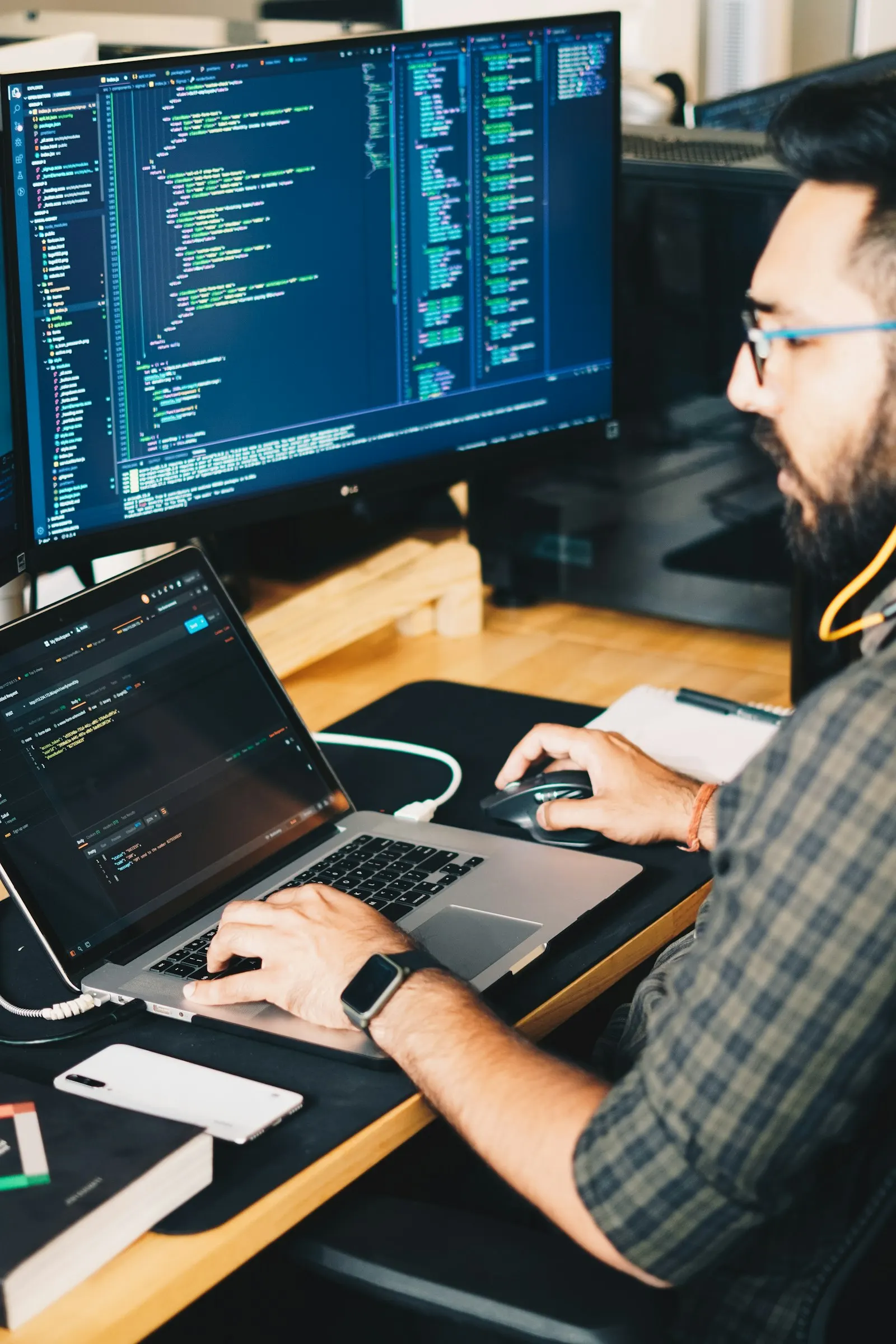 A Flutter developer working through code across two monitors in a dim studio.