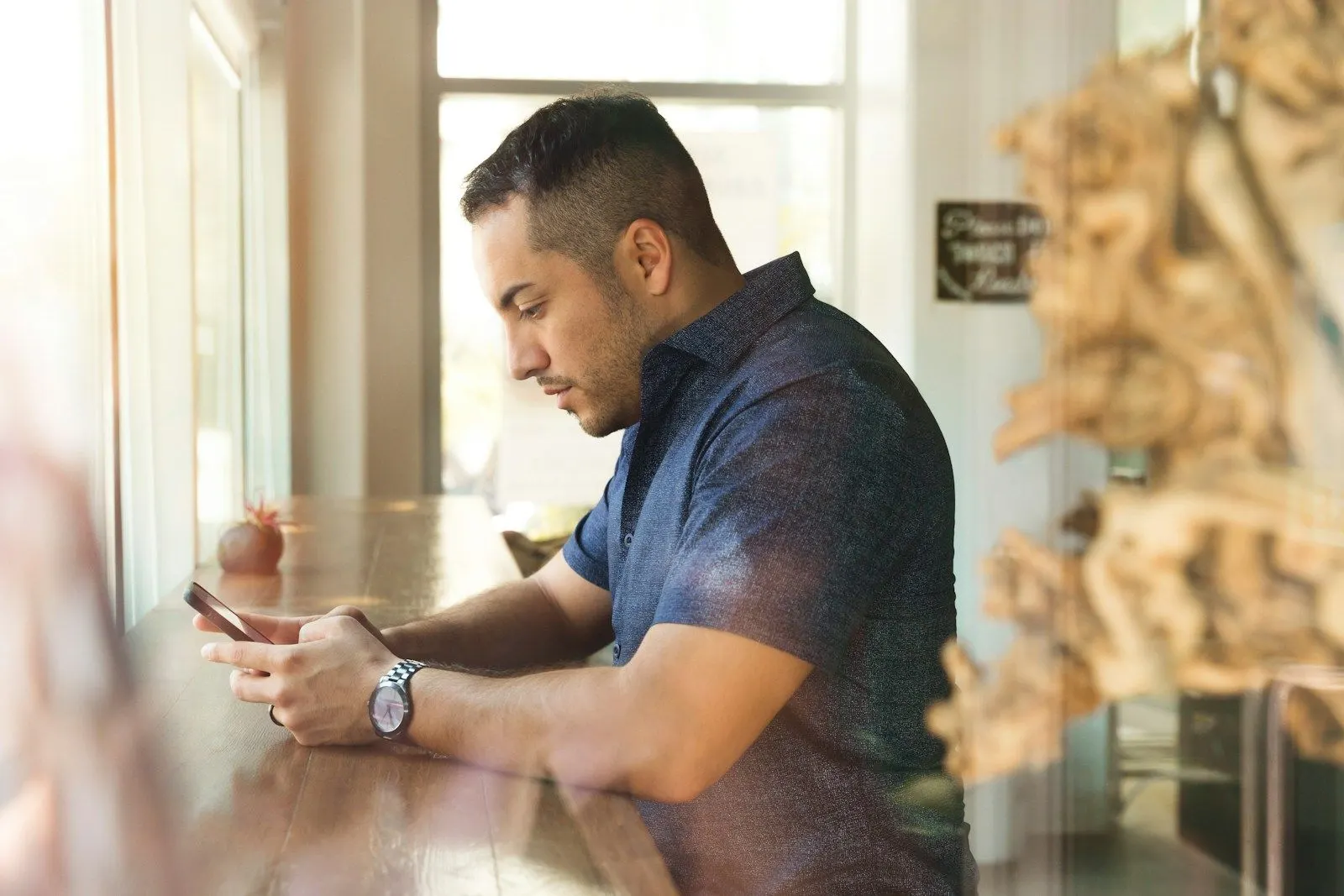 A Flutter UI engineer typing on his phone at a counter.