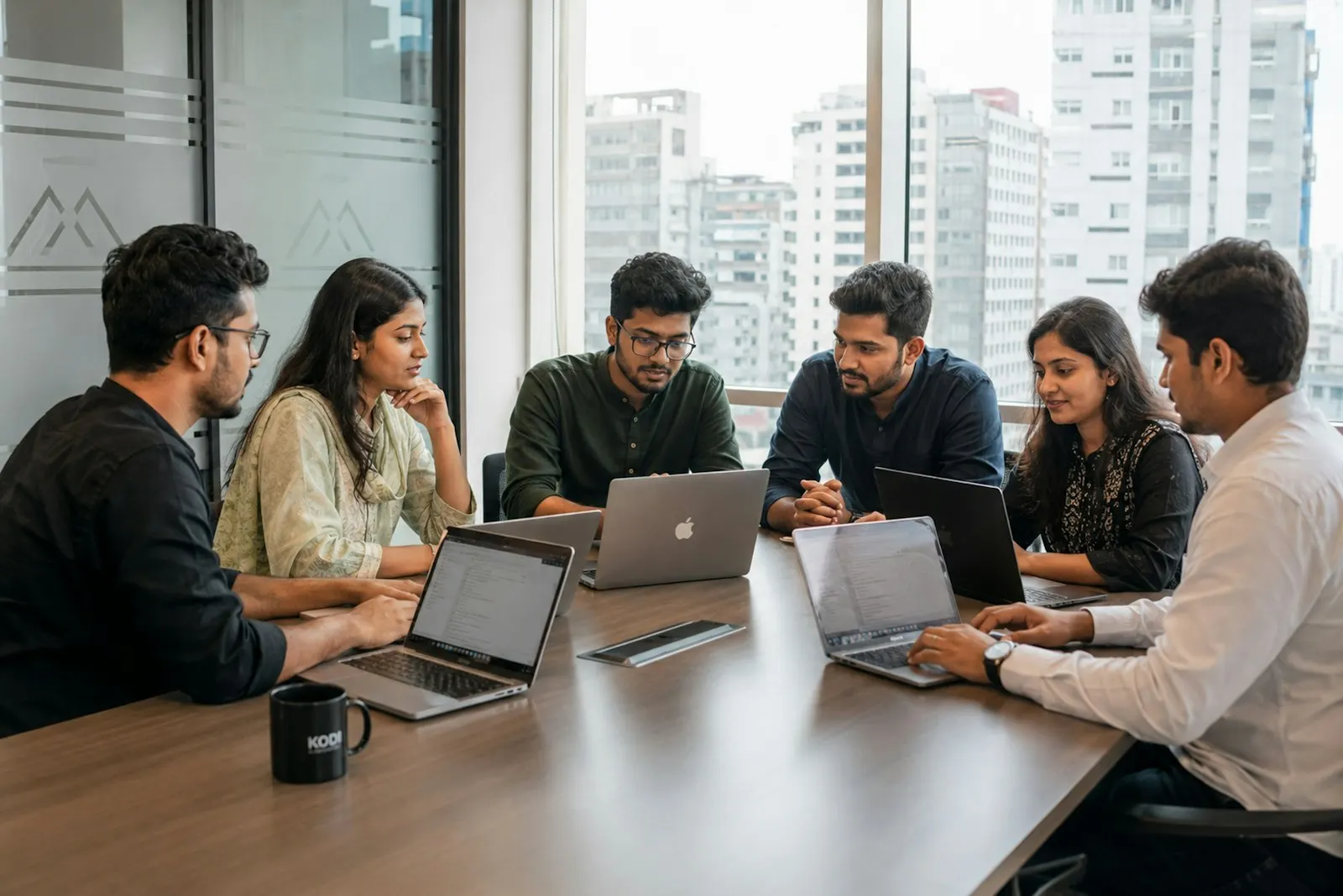 AI developers reviewing eval results on their laptops around a meeting table.