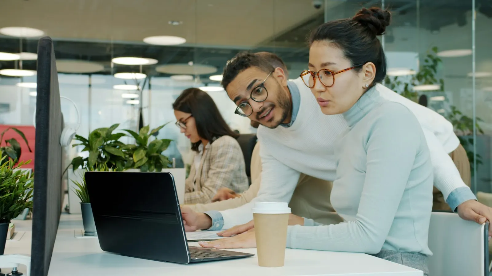 Two AI developers talking through a result on a laptop in a bright office.