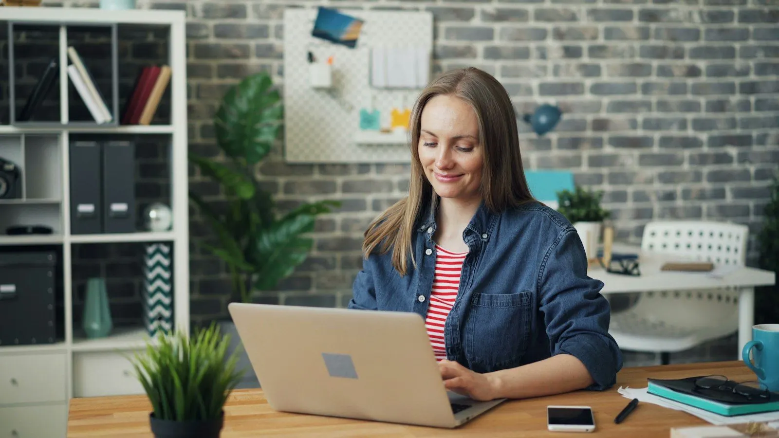 An AI solutions architect in a denim shirt working on her laptop at a home desk.