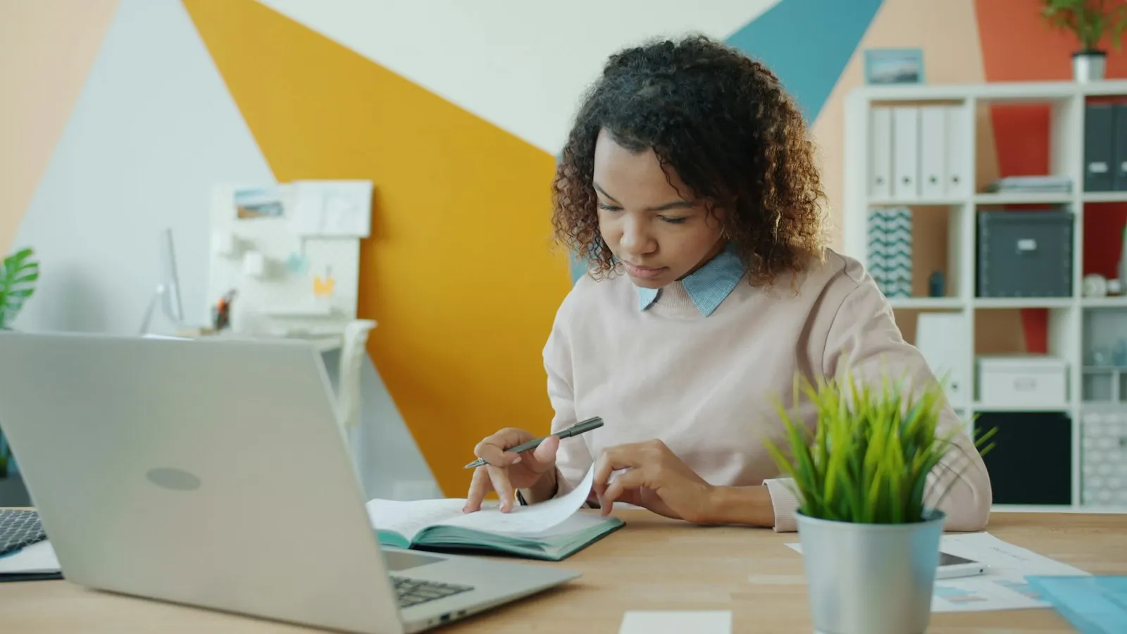 A Machine Learning developer taking notes beside her laptop at a bright desk.