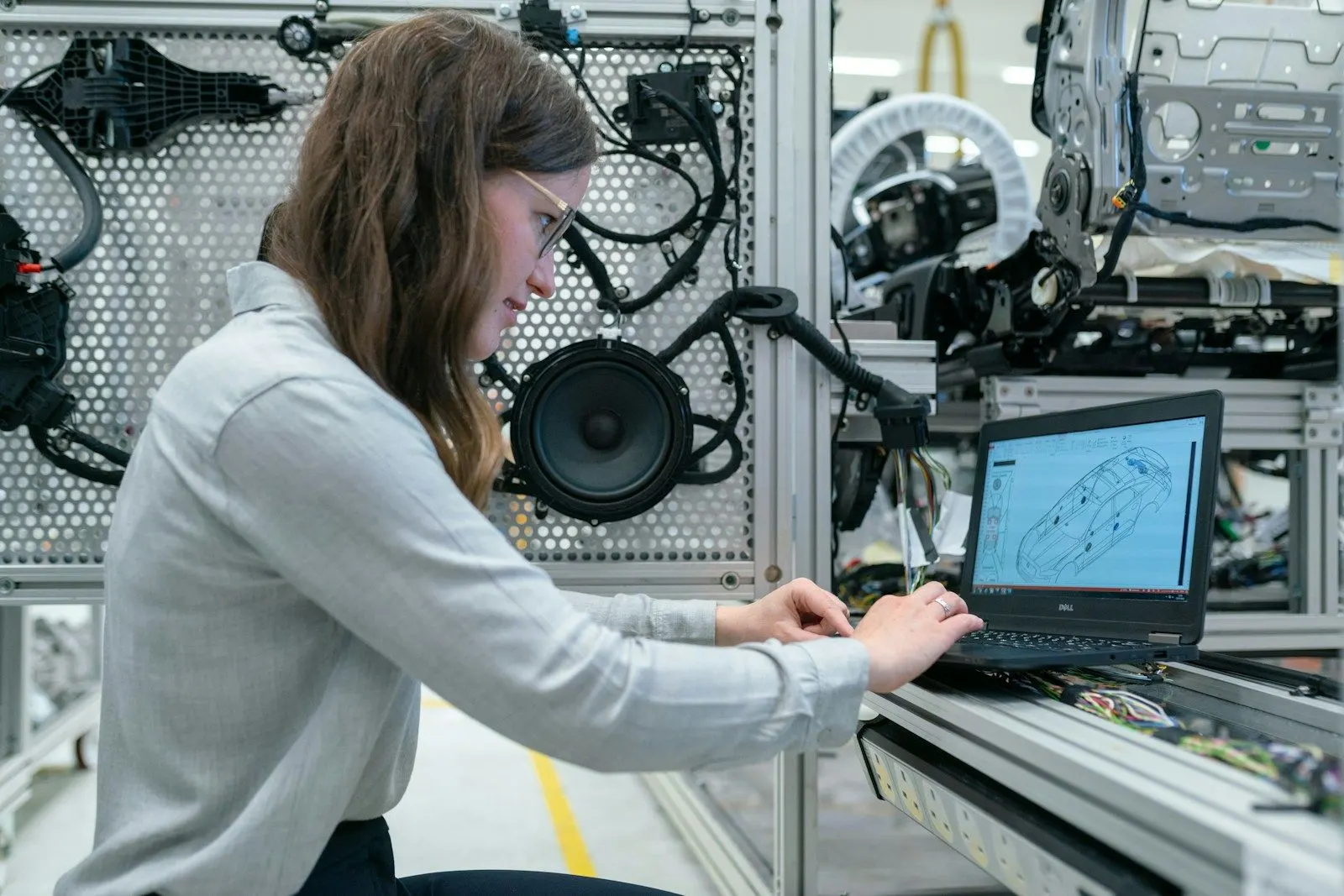 An applied data scientist working on a laptop beside robotics equipment in a lab.