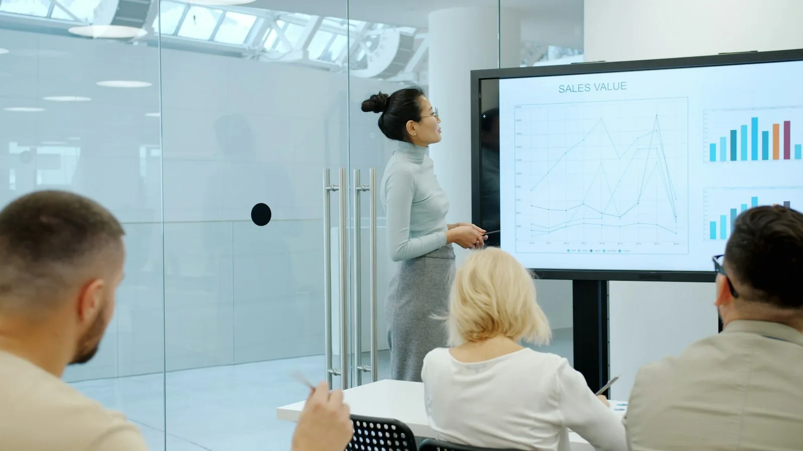 A hired Data Engineer walks colleagues through a pipeline chart on a wall screen.