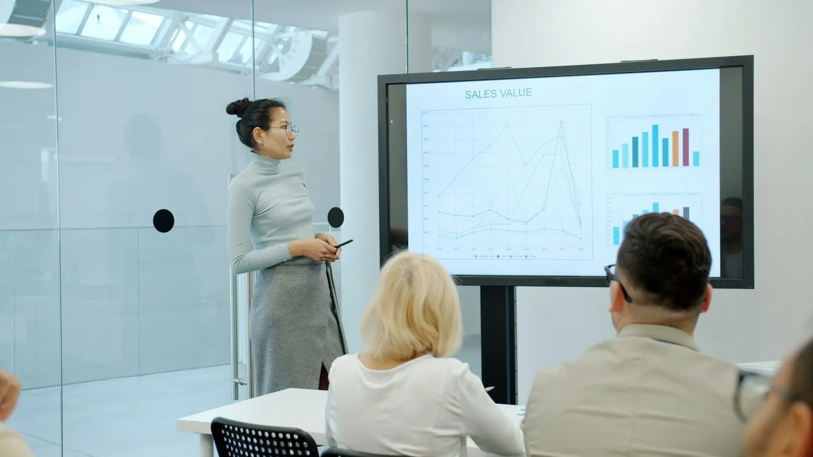 A senior data engineer presents a pipeline chart on a large screen to colleagues.