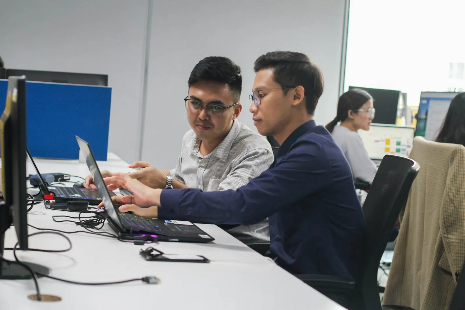 Two QA Automation Engineers review a test run together on a laptop.