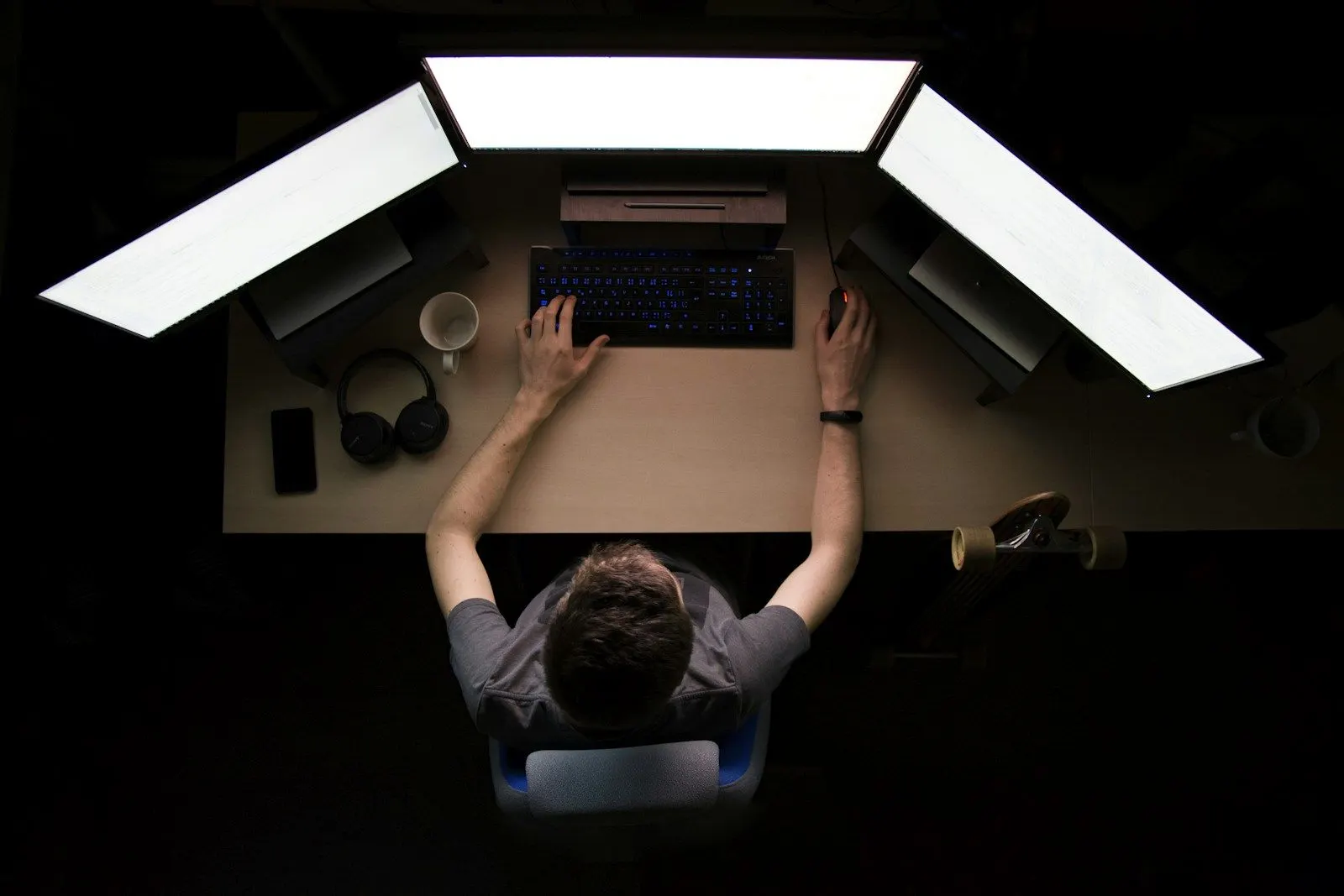 Overhead view of a performance test engineer working at a desk with three large monitors.