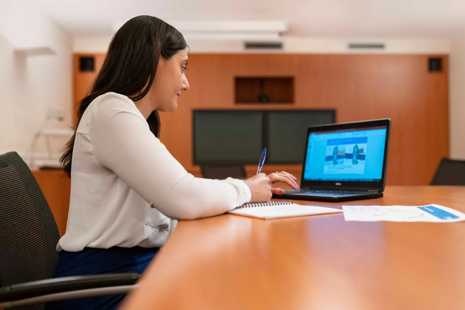 A US onshore AI developer works through a problem on her laptop at a meeting table.