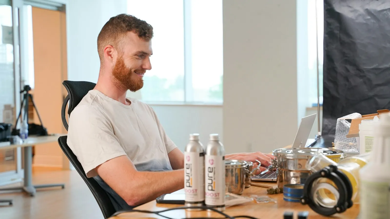 A US onshore full-stack developer smiles as he works at a desk in a bright studio.