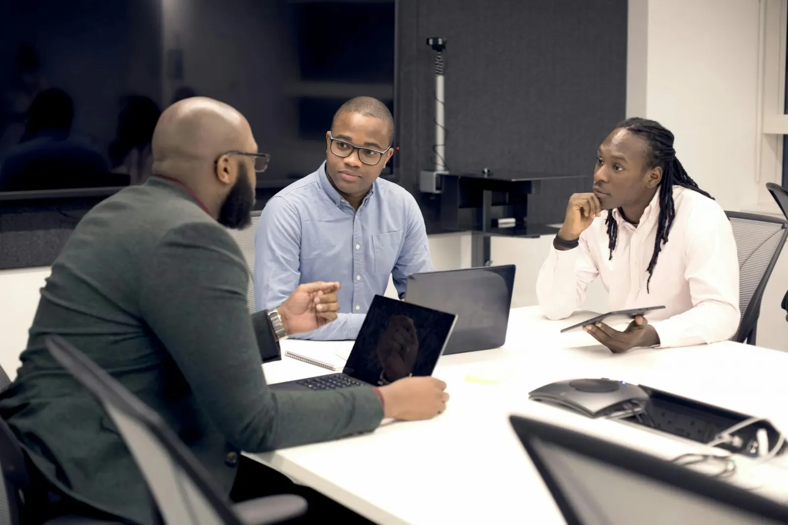 Three colleagues talk through an onshore developer hiring plan at a meeting table.