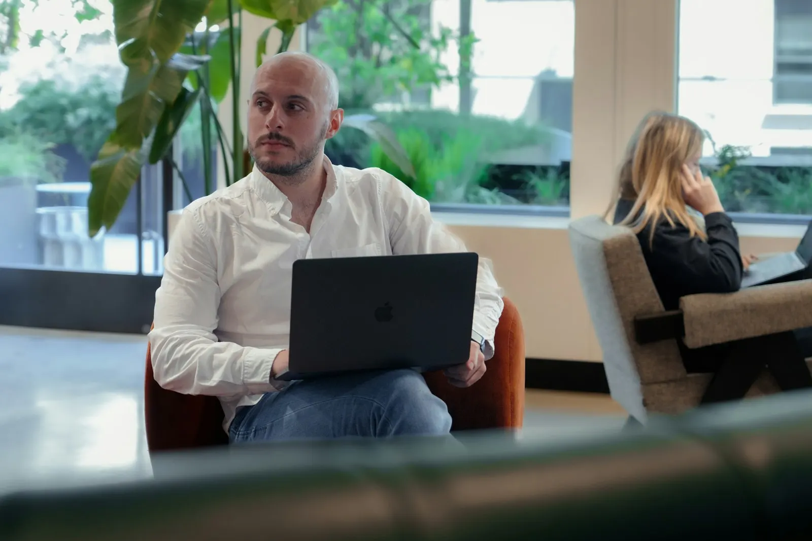 A US onshore developer with a laptop on his knees listens in a bright office lounge.