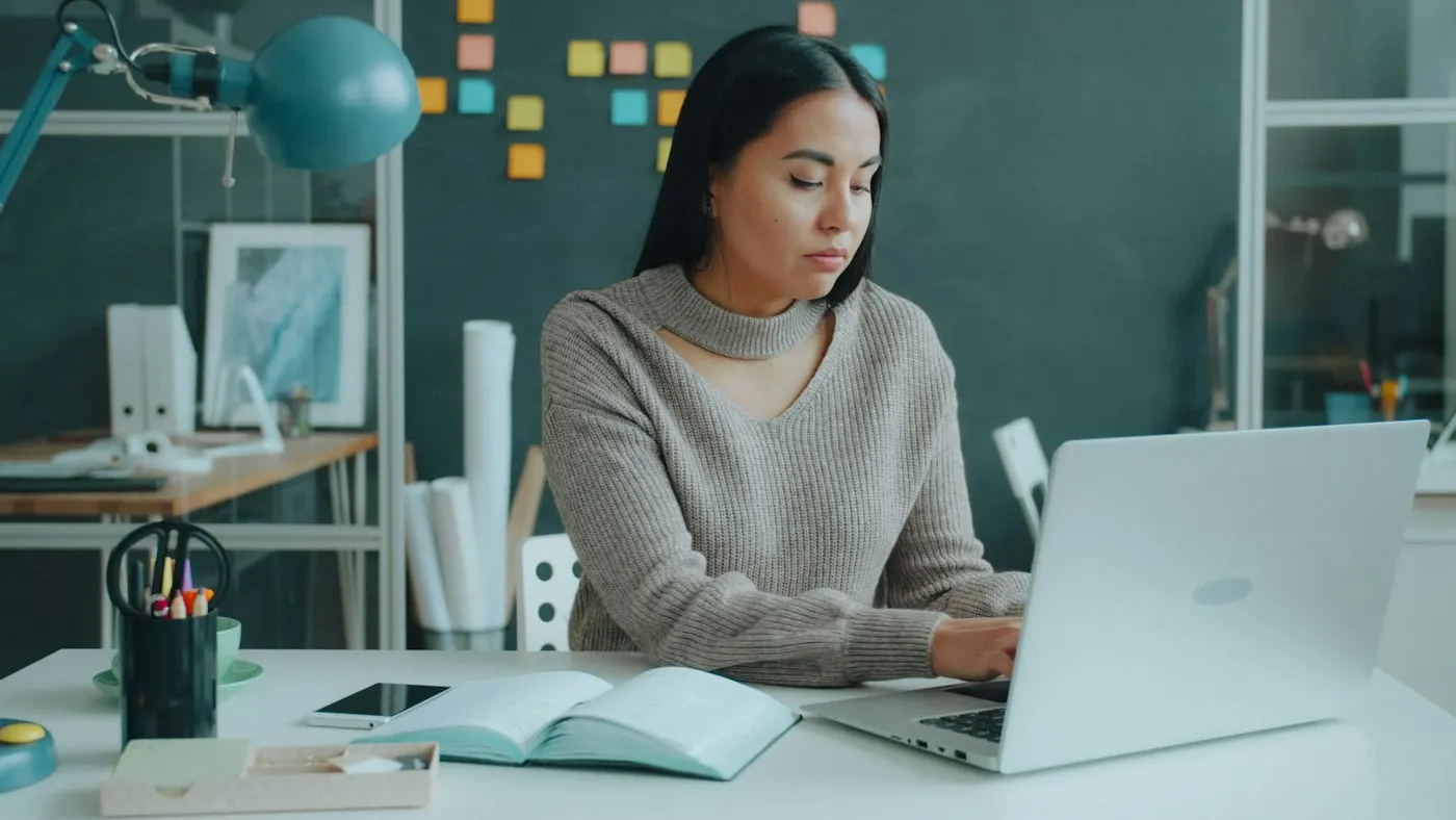 A nearshore data engineer in Mexico types on a laptop at a bright desk.