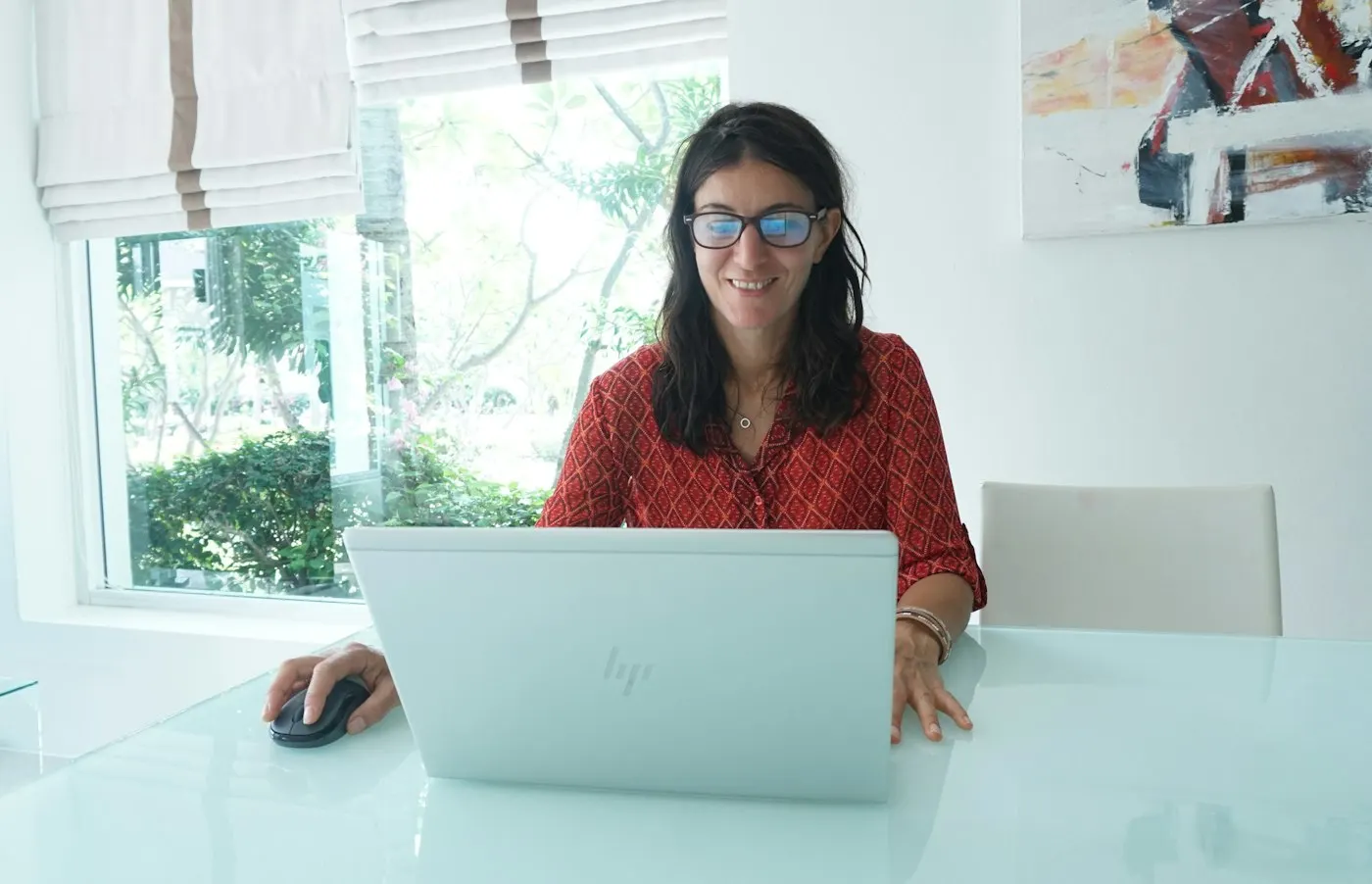 A nearshore AI developer in Mexico smiles at her laptop in a bright room.