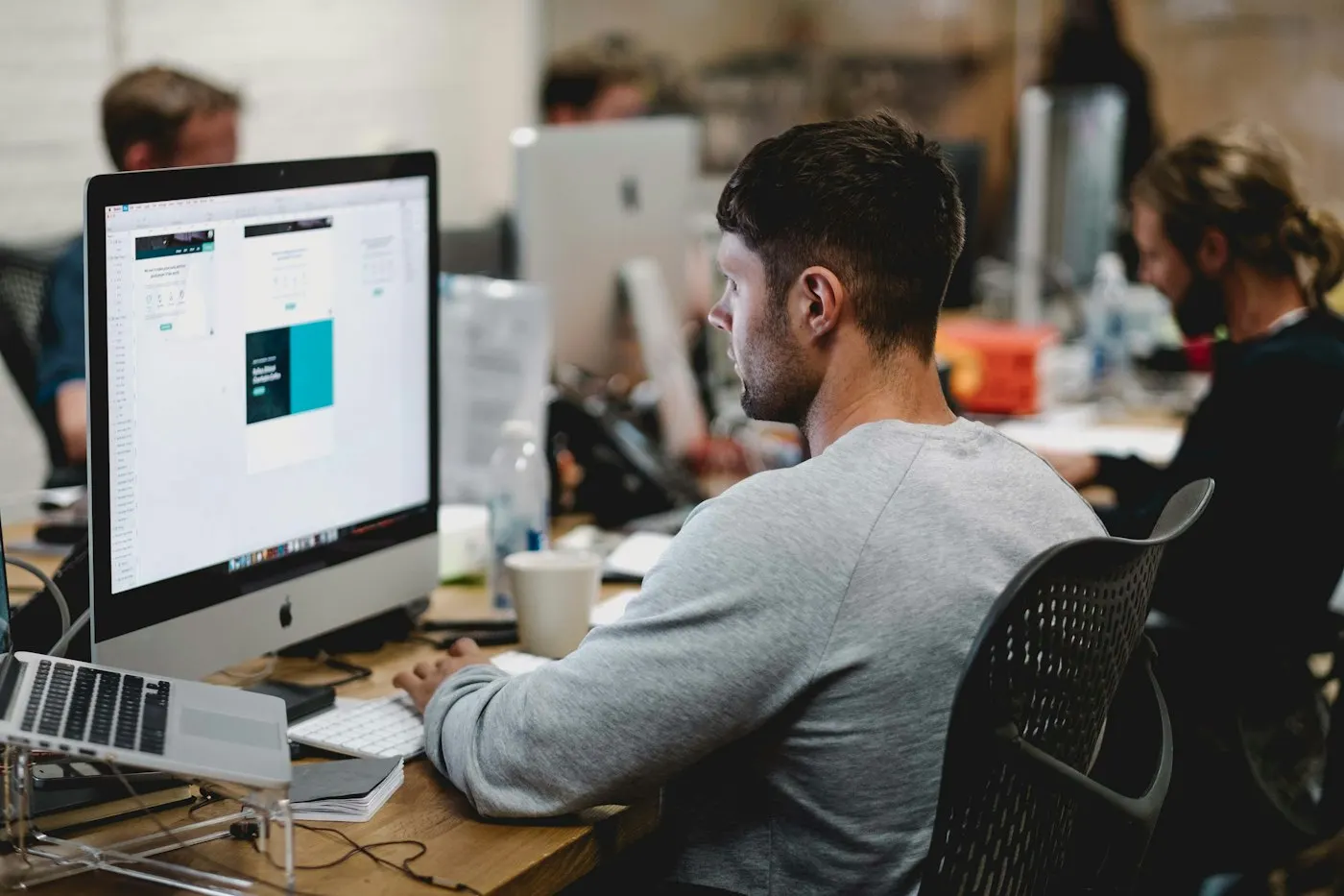 A nearshore full-stack developer in Mexico works at a desktop in an open-plan office.