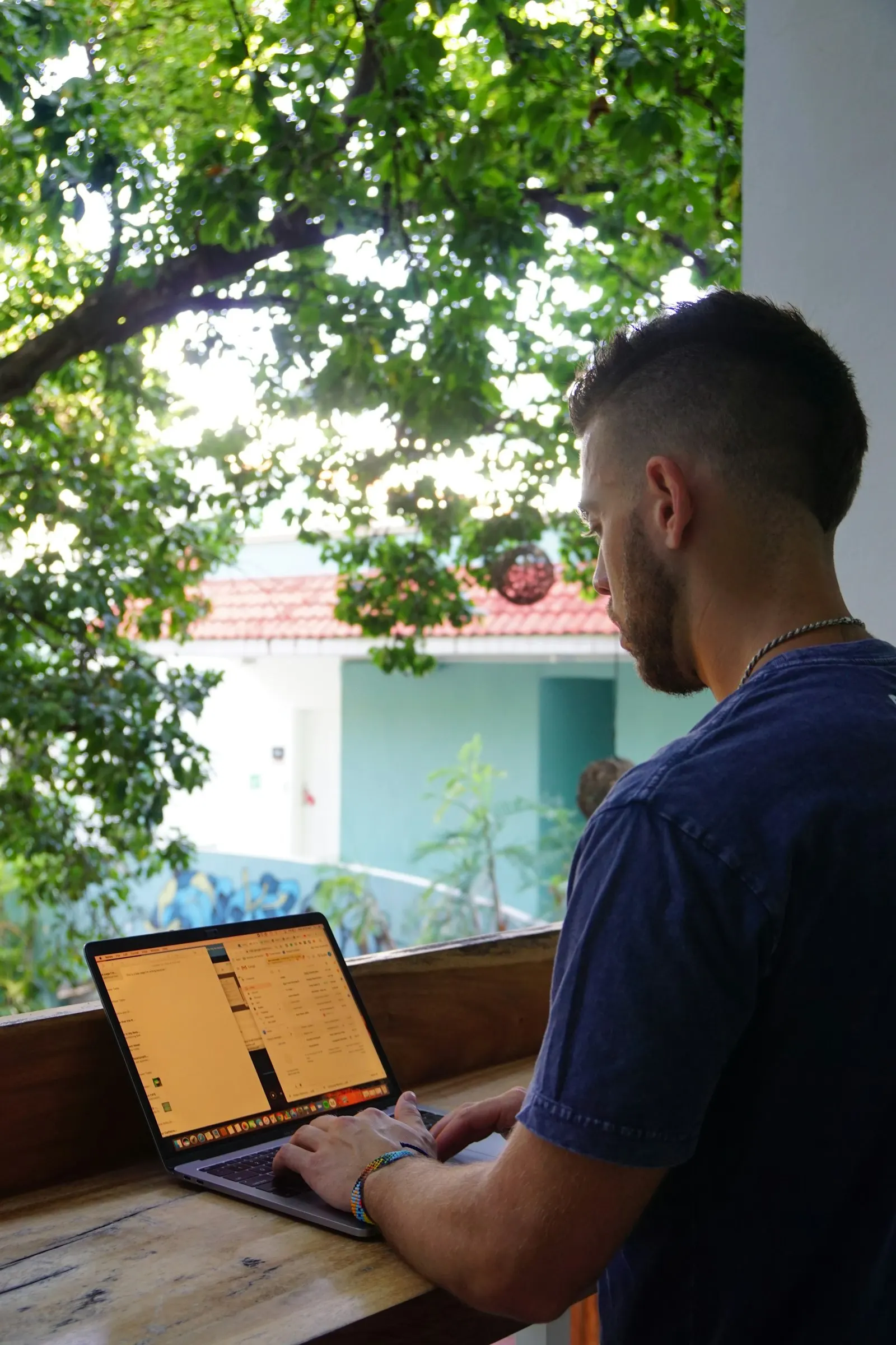 A nearshore back-end developer in Playa del Carmen, Mexico, works at a laptop on a terrace.