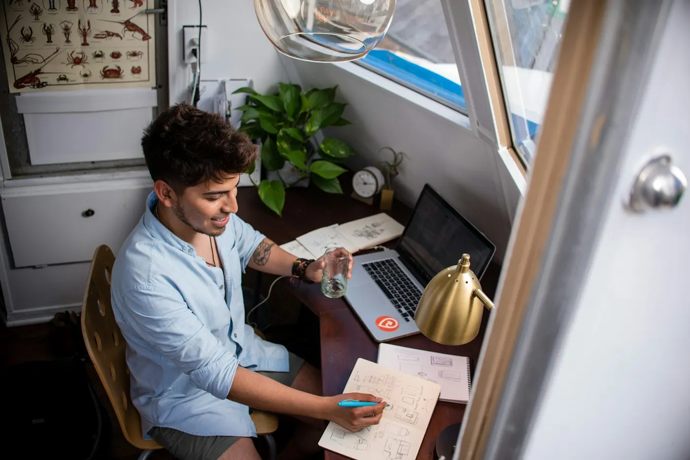 A nearshore developer in Mexico plans his next task at a desk beside a window.