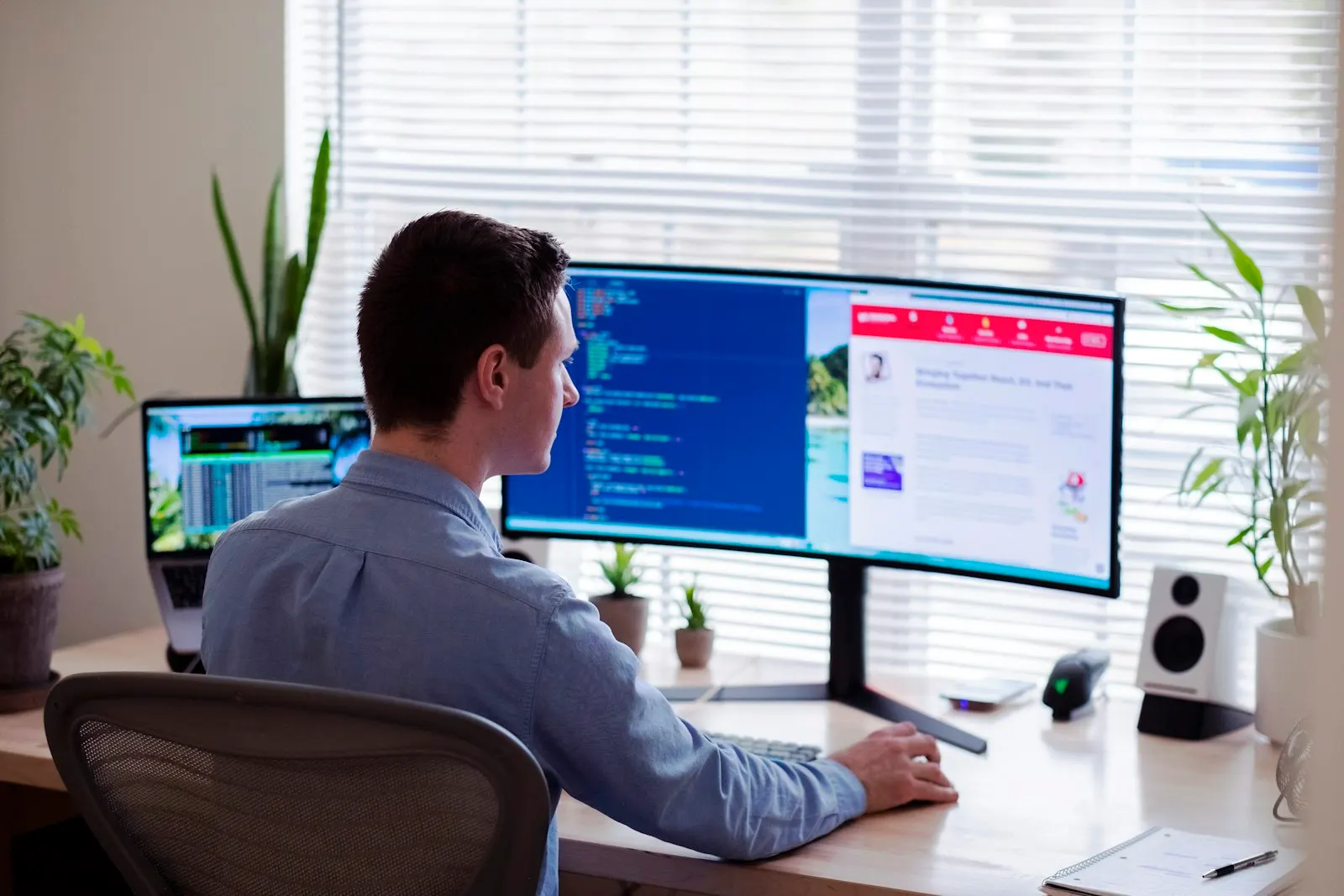 A nearshore back-end developer in Canada works at a wide monitor in a sunny office.