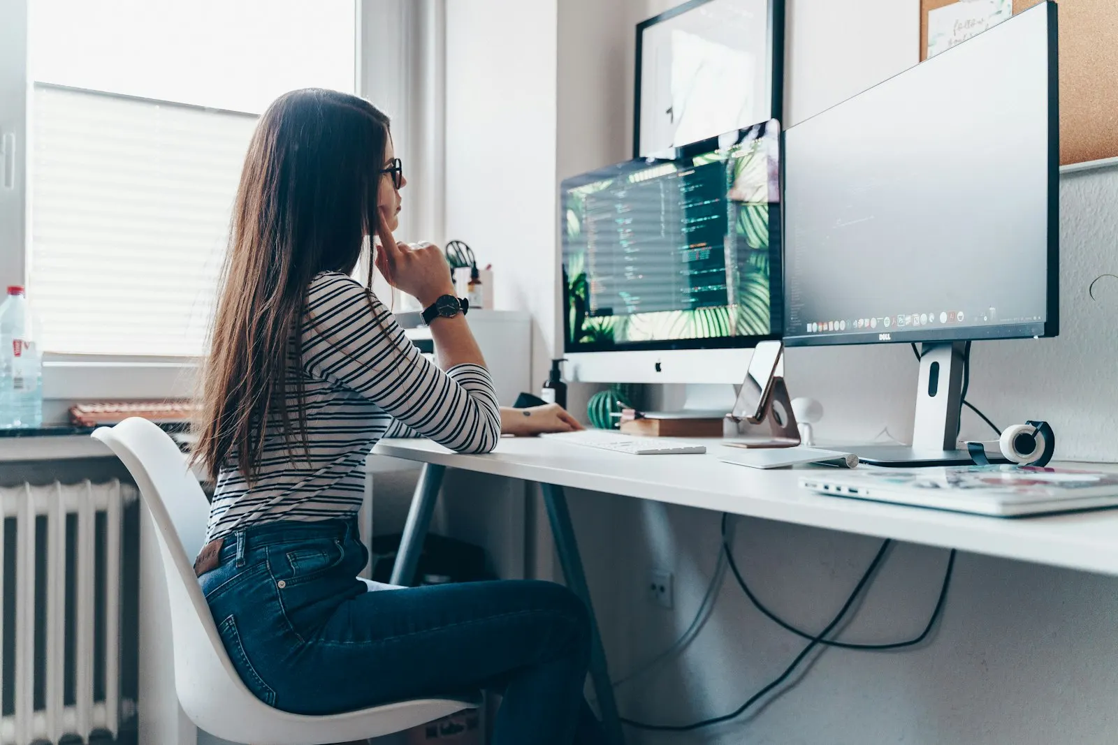 A nearshore data engineer in Canada thinks through a problem at a desk with two screens.